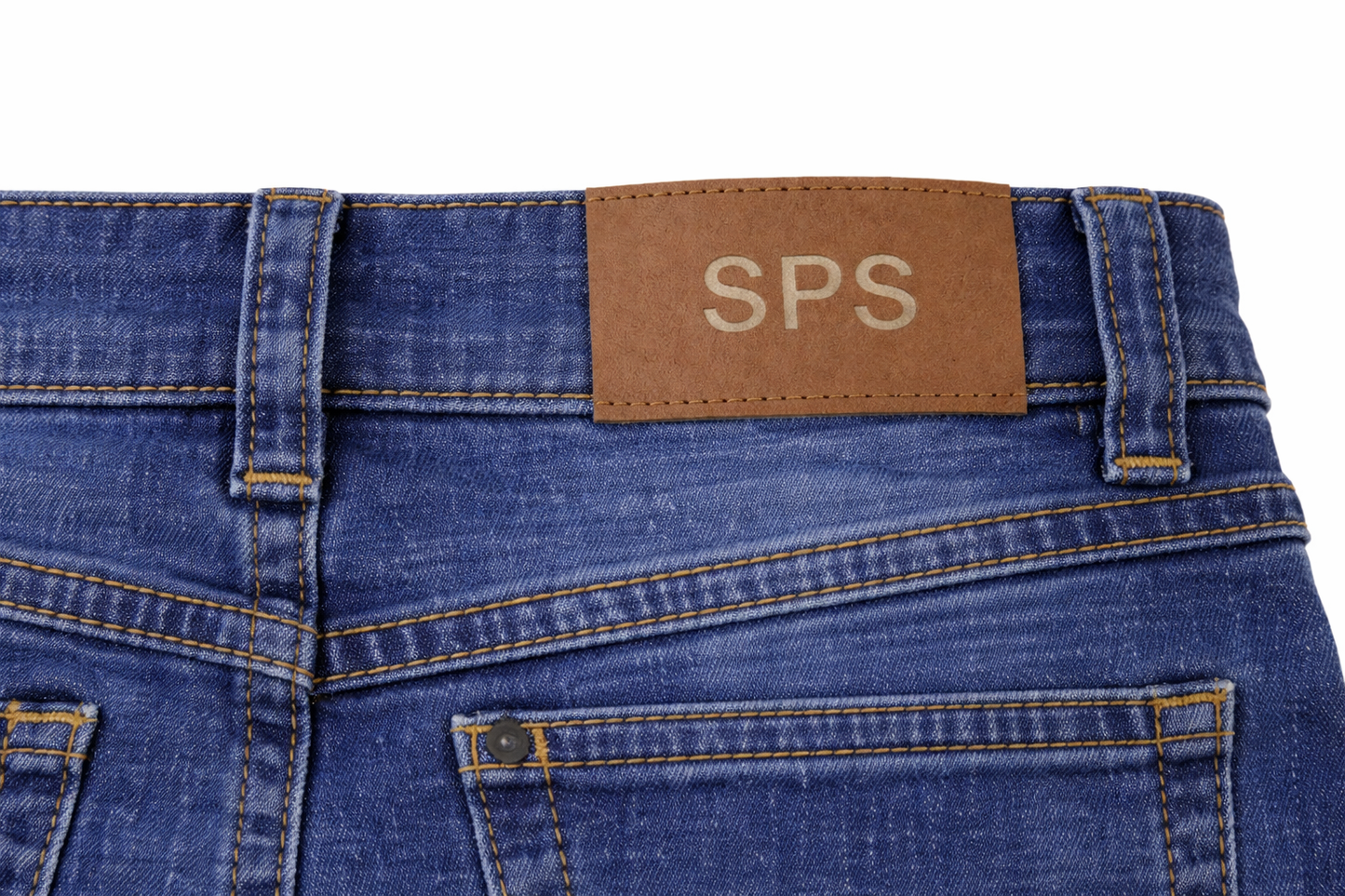 sps-kids-denim-jeans-back-logo-detail Close-up of blue jeans with a brown label displaying 'SPS' on a white background